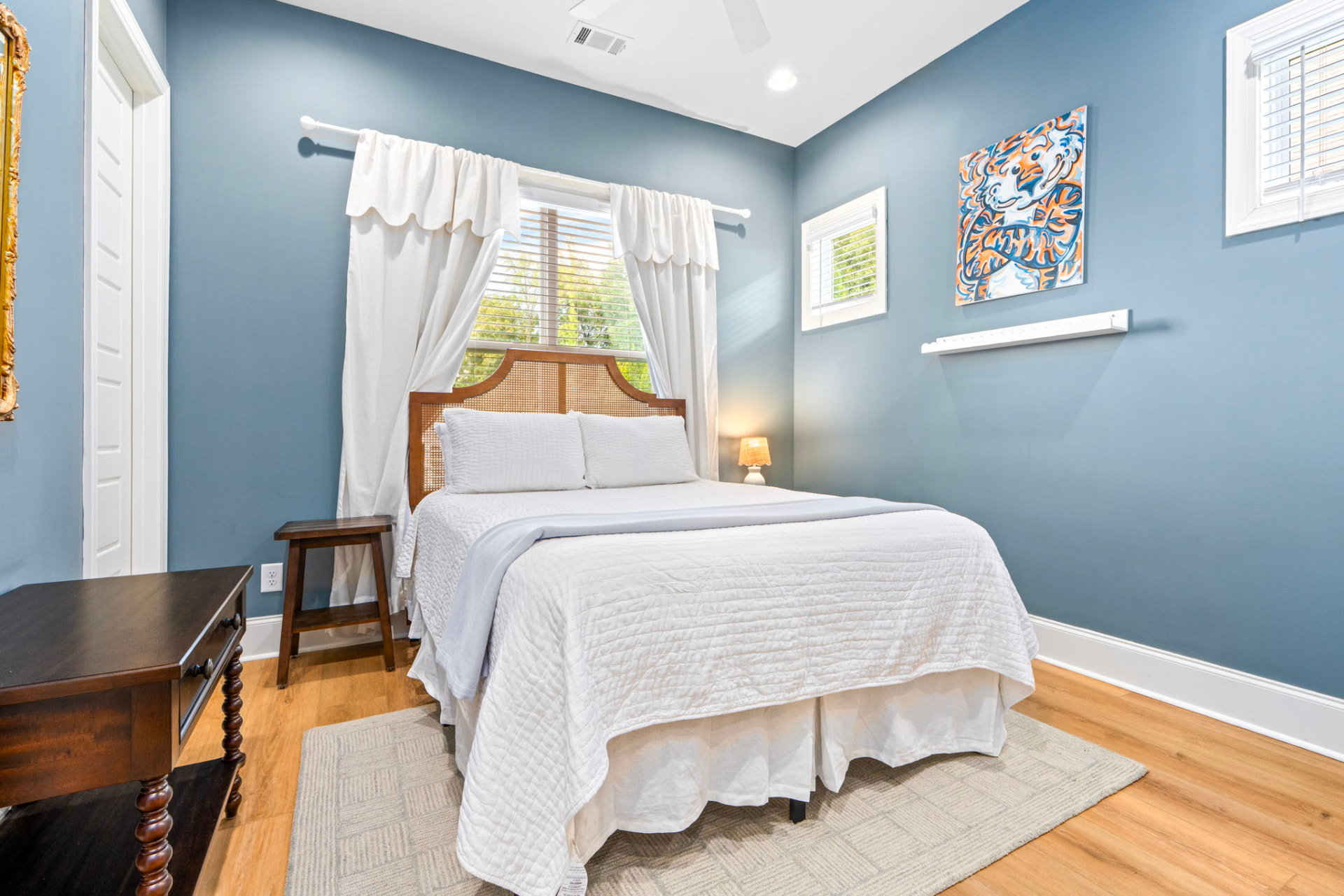 Downstairs bedroom 2 with a queen bed, rattan headboard, blue walls and Auburn tiger art