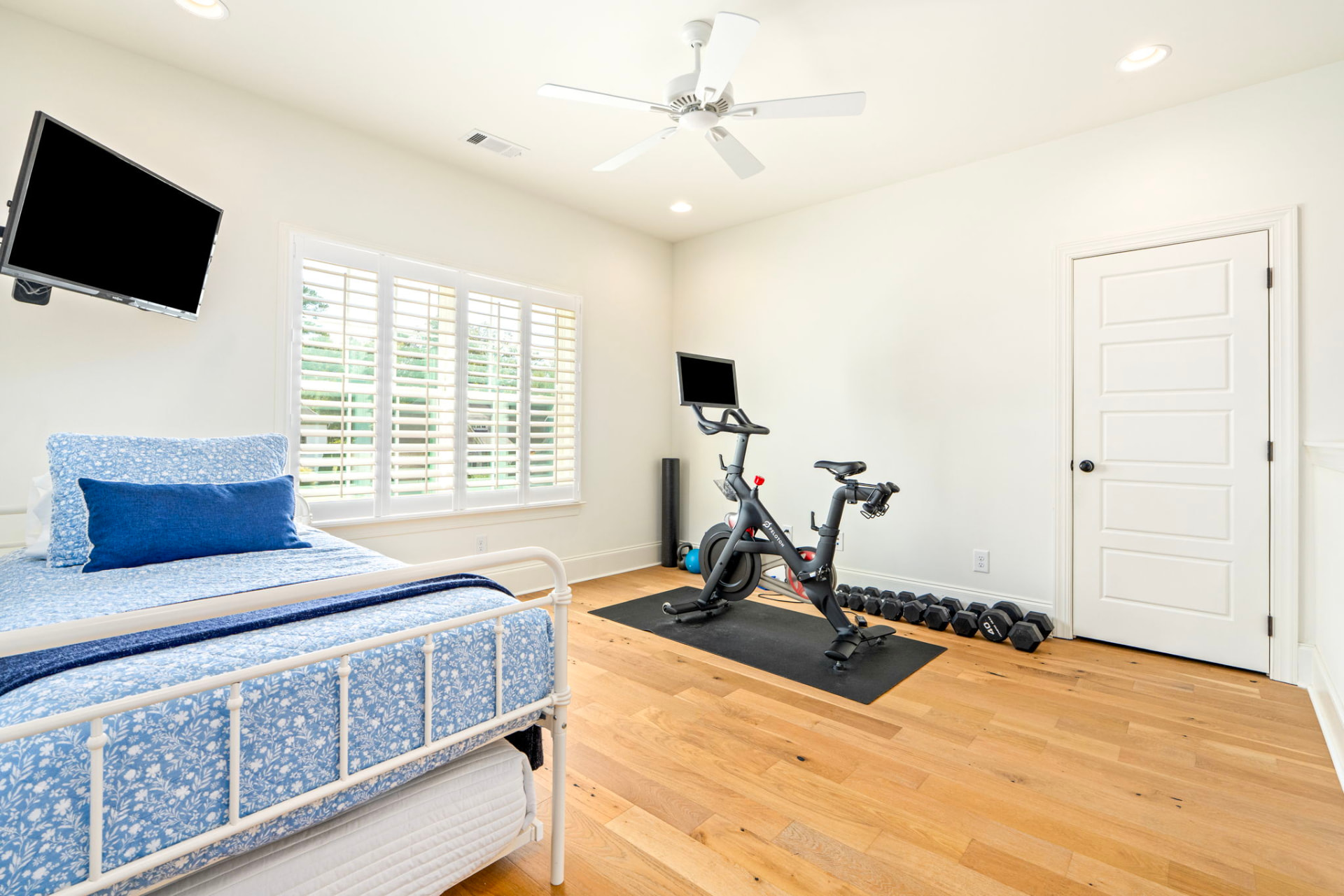 Upstairs loft bonus room with a day bed, mounted TV, Peloton bike and free weights