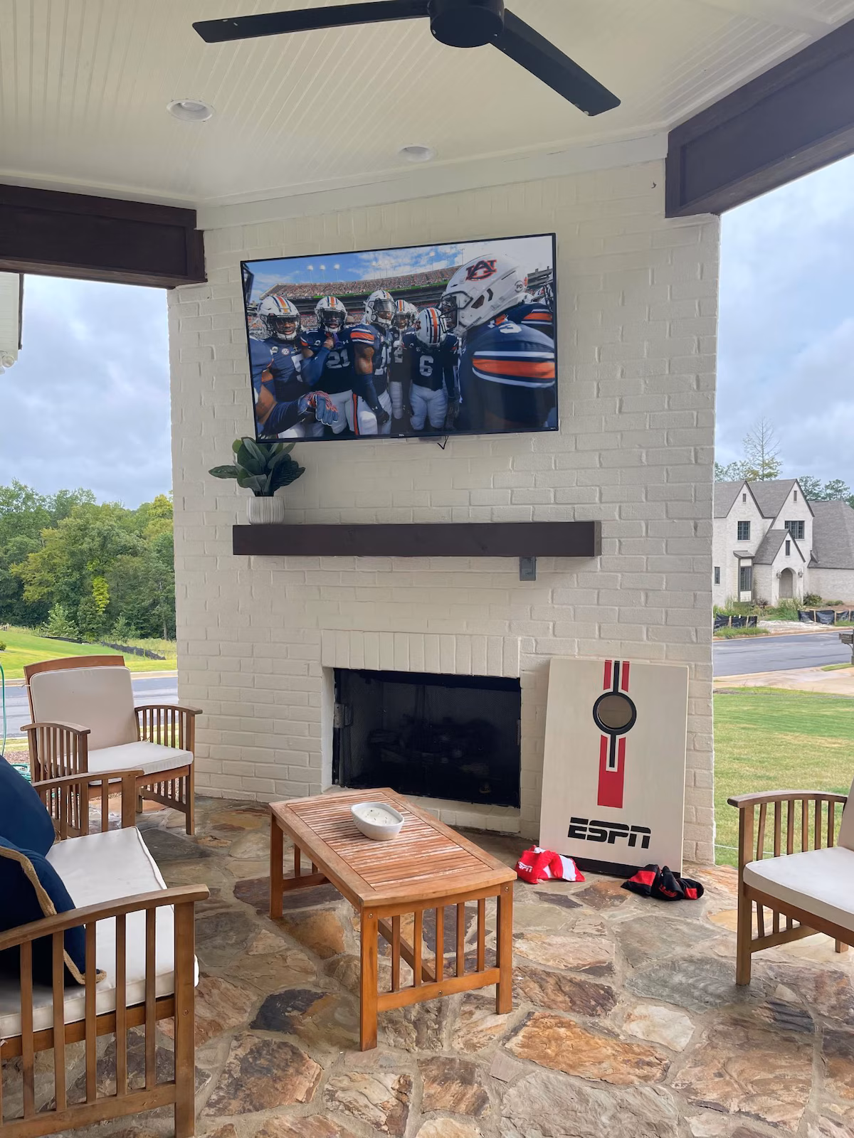 Covered back porch with an outdoor fireplace, mounted TV and lounge seating