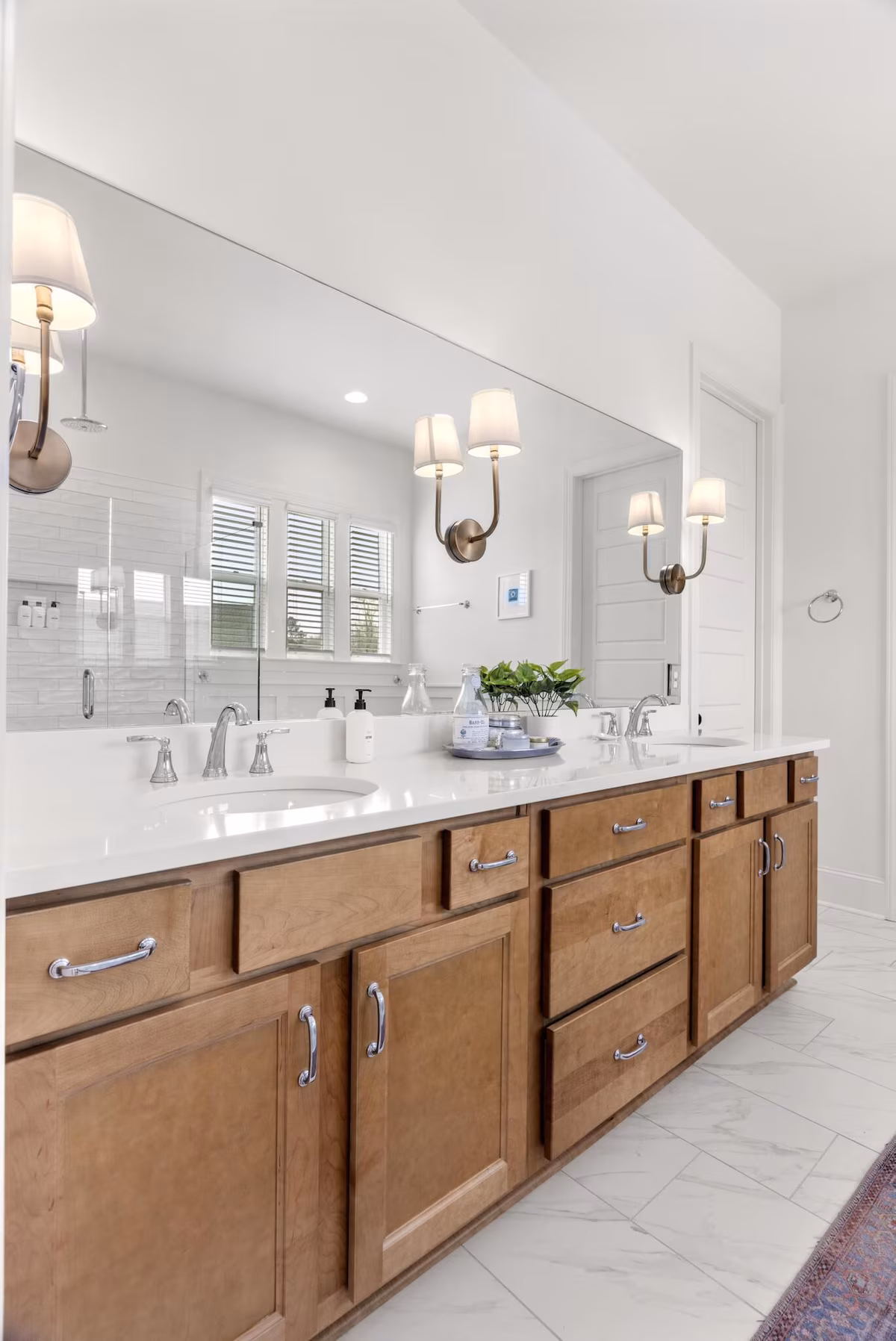 Primary bathroom with a double vanity, large mirror and tiled shower