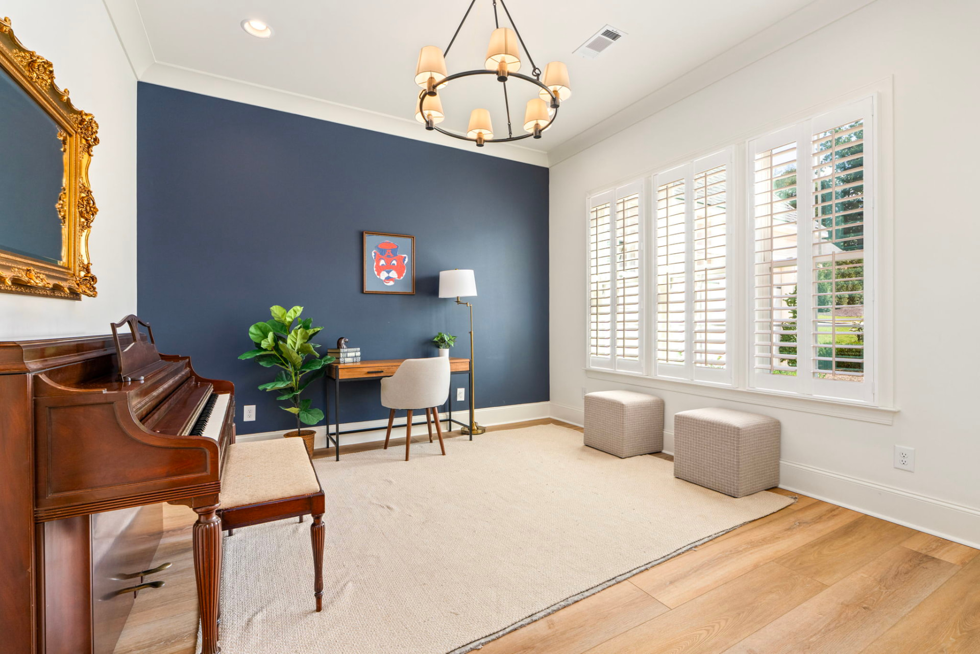 Office and music room with an upright piano, navy accent wall, writing desk and Auburn tiger art