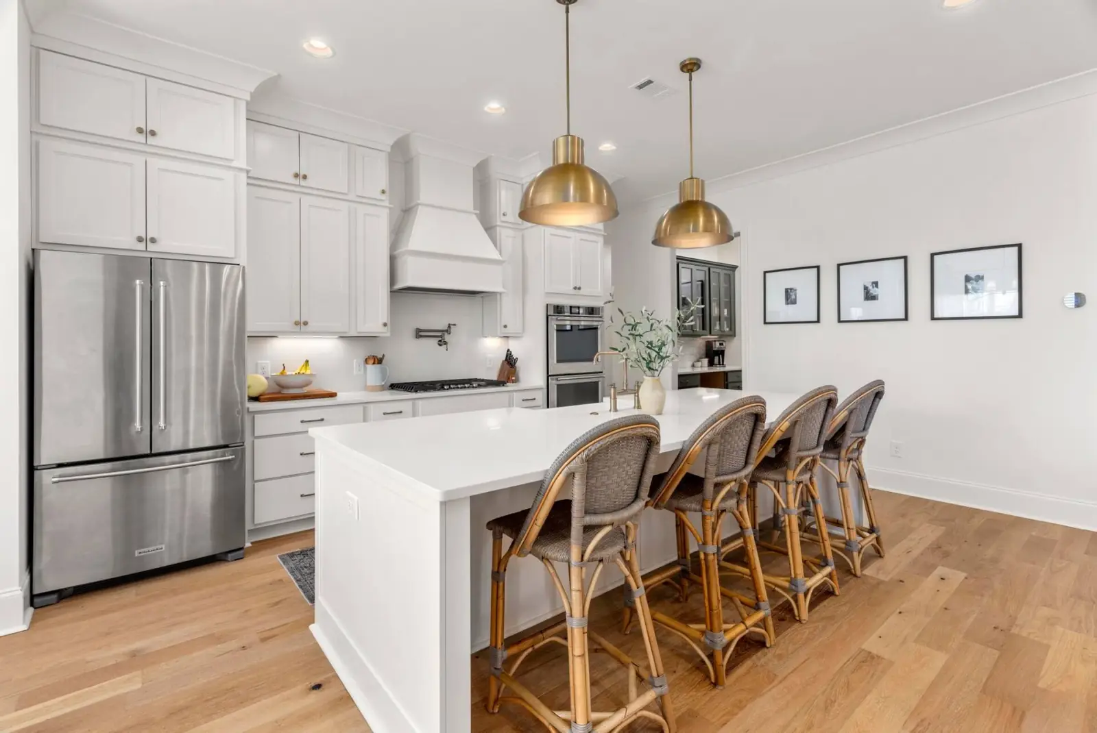 Chef's kitchen with a white quartz island, brass pendant lights, gas range and stainless refrigerator